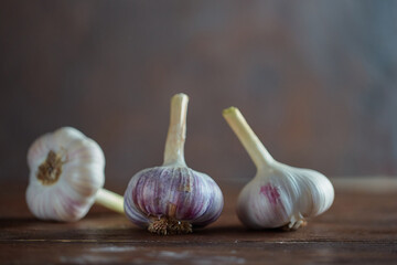 Three ripe heads of fresh garlic on a dark wooden background. Folk medicine for viral and colds