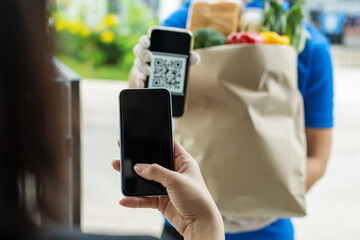 hand customer using digital mobile phone scan QR code paying for buying fresh food set bag from food delivery service man, express delivery, digital payment technology and fast food delivery concept