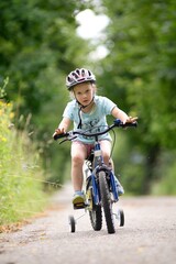 Fototapeta premium The first bike ride a little girl learns to ride a bicycle.