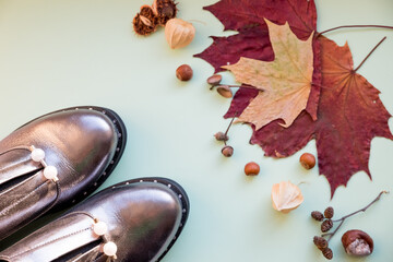 Autumn look with shiny boots on pastel background. concept Autumn, fashion composition. Casual boots with fallen leaves. fall season concept. stylish sneakers with pearls. women's shoes.Copy space