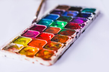 watercolor palette of colors, the child draws and mixes colors with a brush