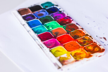 watercolor palette of colors, the child draws and mixes colors with a brush
