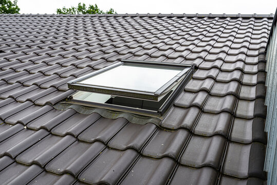 One open roof window in the attic, visible anthracite ceramic tiles.