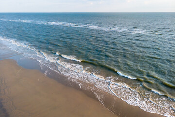 Drone view on the coastline and surf on the sandy beach of the island of Juist in the North Sea Germany.