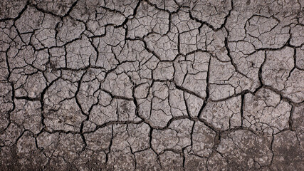 Dark dry cracked earth background. Dried mud texture.