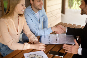 Real estate agent and clients shaking hands after signing property agreement