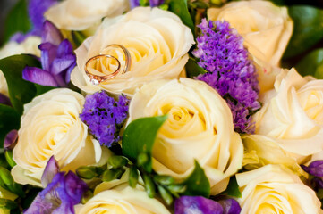 Wedding rings of the bride and groom on the background of a bouquet