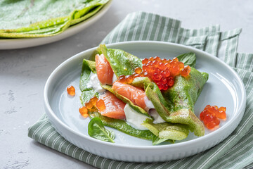 Green spinach crepes with smoked salmon, red caviar and yogurt sauce