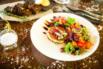 Goat cheese salad. Strawberry-melon salad with chilli, apple-orange sauce, fig jam on white plate. Delicious meat food closeup served on a table for lunch in modern cuisine gourmet restaurant