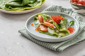 Green spinach crepes with smoked salmon, red caviar and yogurt sauce