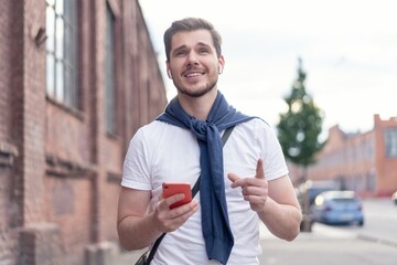 Handsome smiling man listening to music while walking in the city.