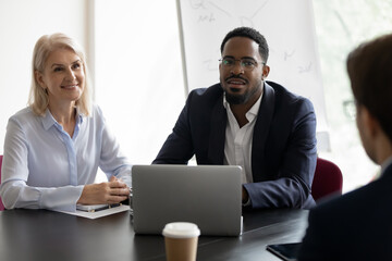 Diverse meeting attendees listening speech of speaker during group meeting in office, serious...
