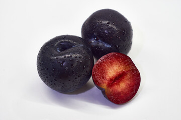 Two and a half plums on a white background.