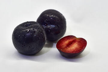 Two and a half plums on a white background.
