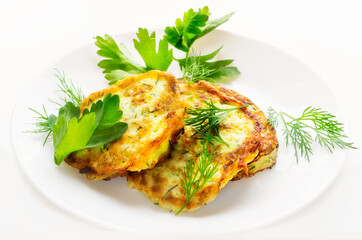 zucchini pancakes on a white plate with parsley leaves.