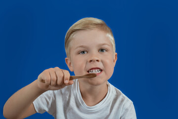 Boy brushing his teeth on blu background