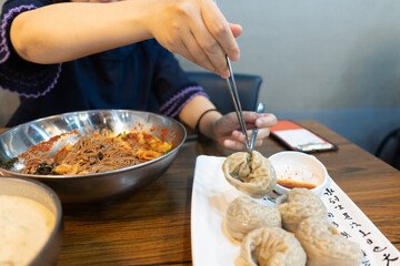 Woman eating steamed dumpling at restaurant
