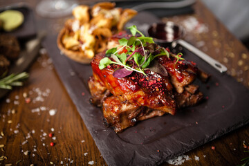 Pork ribs cooked at low temperature. Blackcurrant sauce, parsnip chips with Parmesan cheese. Delicious healthy meat food closeup served on a table for lunch in modern cuisine gourmet restaurant