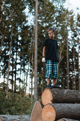 Teenager standing on the wood pile with forest in the background.