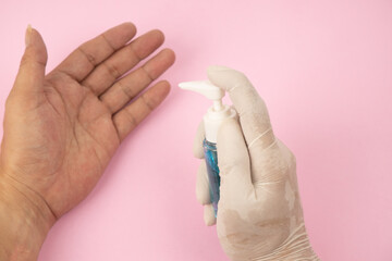 Hand of lady that applying alcohol spray or anti-bacteria spray to prevent the spread of germs, bacteria and virus. Personal hygiene concept. , Isolated on pink background