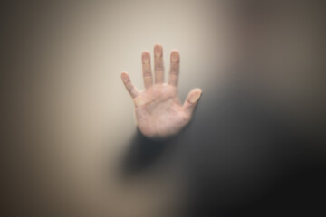 Blurred male hand behind matte glass wall