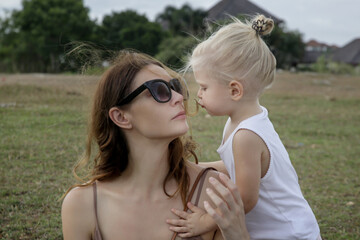 Outdoor candid portrait of mother with her toddler girl. Family time in nature, bonding and affection concept.