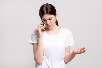 Disturbed woman portrait. Phone call. Annoyed lady having negative talk conversation isolated on neutral copy space. Distance communication. Information technology.