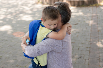 Dad accompanies his son to school or kindergarten and hugs him on the street