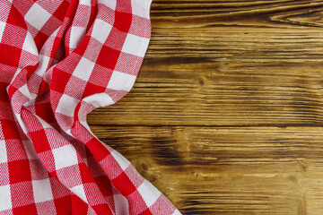 Red folded checkered napkin on rustic wooden kitchen table. Top view, copy space