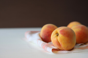 juicy ripe peaches on a rag napkin on a white and brown background.