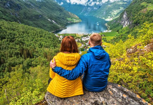 blue yellow couple sitting over Norvegian fjord