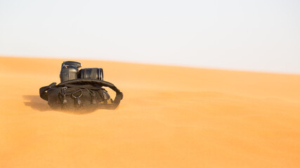 Photographer's bag lies on the hot sand during a sandstorm.