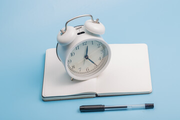 Notebook alarm clock pen on blue background