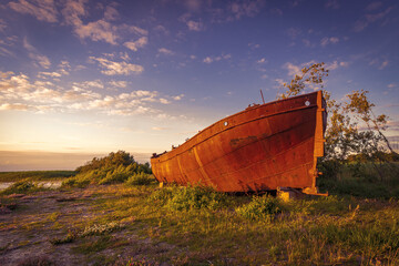 Lonely rusty ship lies deserted on the shore.