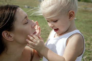 Outdoor candid portrait of mother with her toddler girl. Family time in nature, bonding and affection concept.