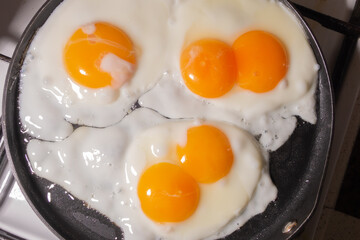 Simple rustic fried eggs in a frying pan top view. Eggs with two yolks. View through steam.