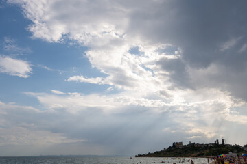 Dramatic clouds over the sea and the beach with people.