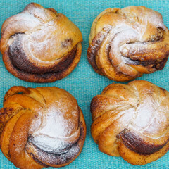 Top view of delicious sweet rolls with filling and topping on turquoise background. Space for text.