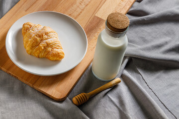 Croissant and milk are placed on a plate in the morning.