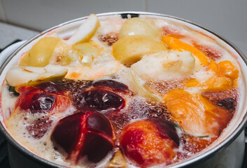 Fruit compote: apricots, plums, apples, cherries are cooked in a metal pan in boiled water with bubbles. Making juice.