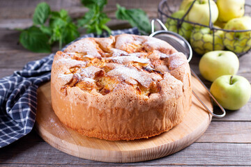 Sponge cake with apples on a wooden board on the table.