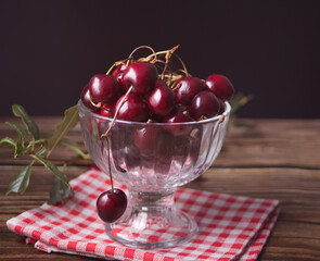 Fresh ripe organic sweet cherry in bowl on rustic wooden table.