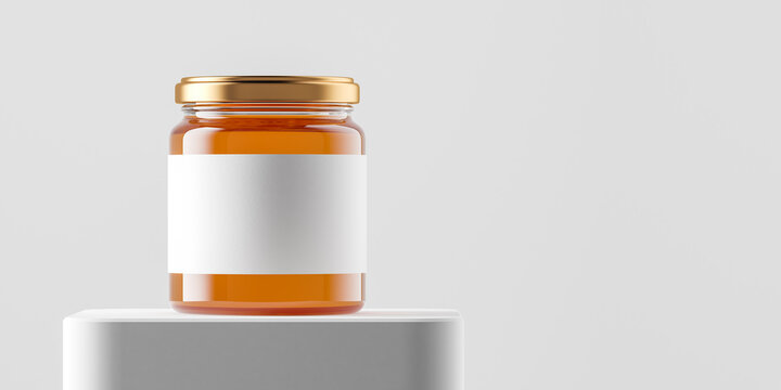 Transparent glass jar with copper metal cap and blank label filled by sweet honey on the podium over white background.