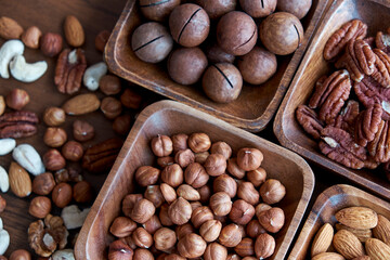 Wooden bowl with mixed nuts on table top view. Healthy food and snack. Walnut, pistachios, almonds, hazelnuts and cashews.