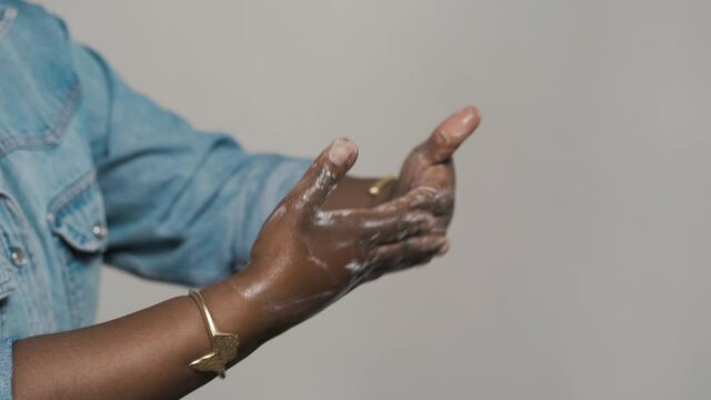 Close up of Black women washing hands with soap on light brown background. Hand washing demonstration for virus protection. Concepts of hygiene, prevention and bacteria protect