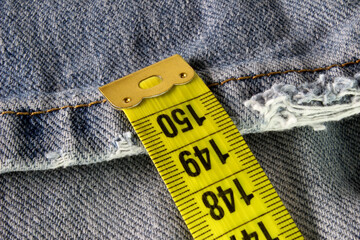 yellow measuring tape on blue jean background