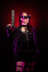 Young woman dressed in a studded leather jacket, a pair of cyberpunk glasses, holding a gun in her hand