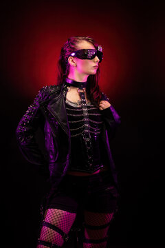 Young woman wearing a studded leather jacket, holding her glasses