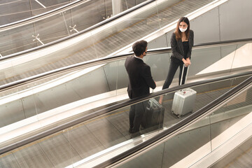 Two Businessman and woman having conversations while wearing face mask on escalator, New normal of people to stay safe and awareness for prevent coronavirus or covid-19 pandemic.