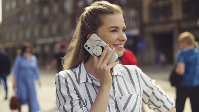 Young blonde woman using phone in a city.
